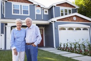 Happy Older Couple Standing in Front of Their Home